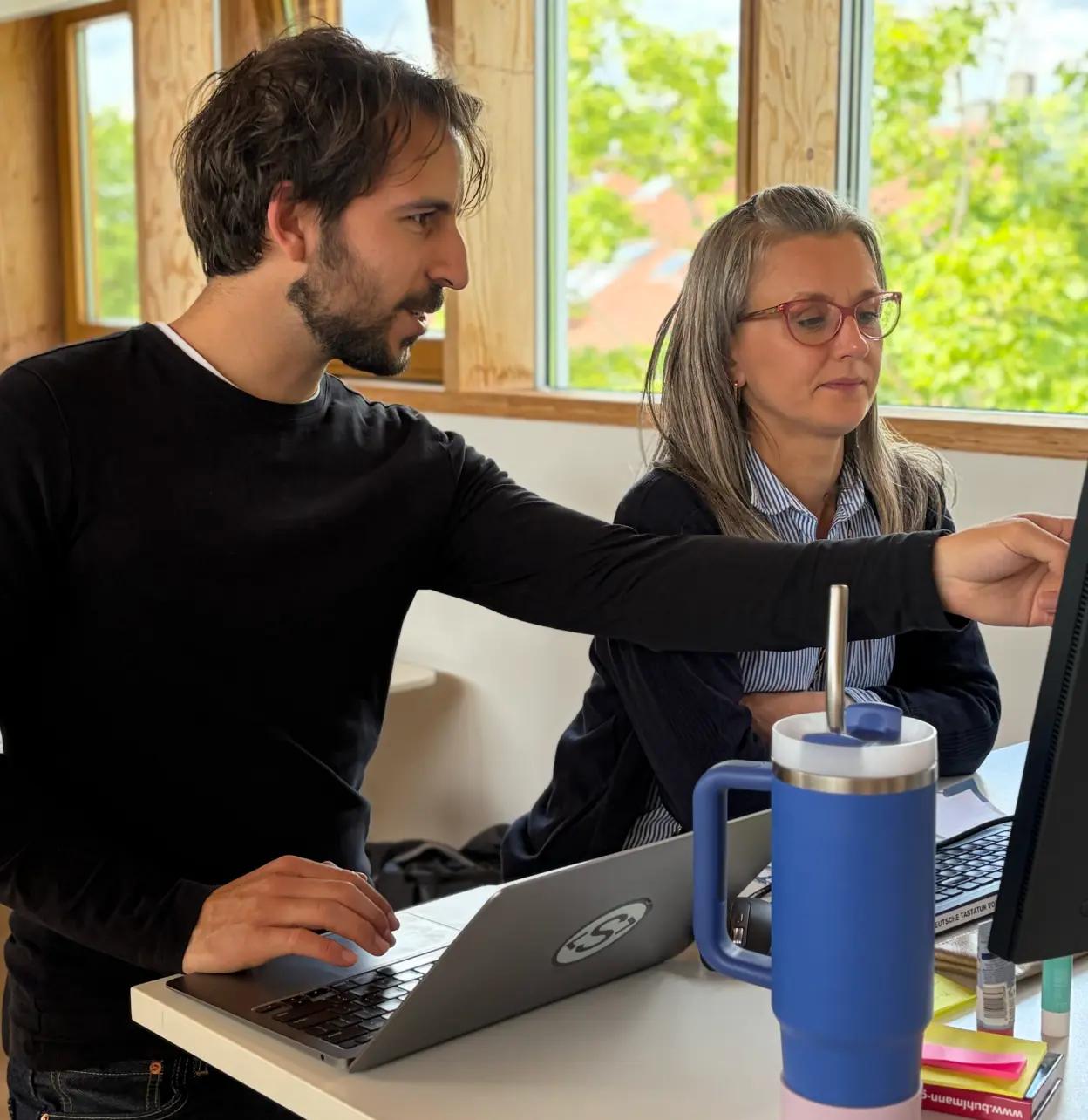 Zwei Menschen arbeiten gemeinsam an einem Bildschirm an einem Kundenproblem